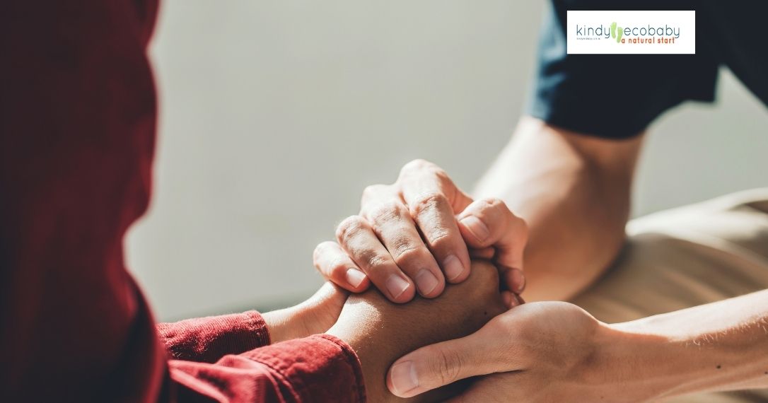 An image depicting a supportive hand gently holding the hand of a new parent, symbolizing comfort and understanding in times of mental health struggles.